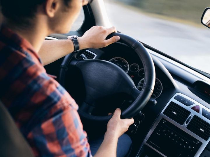 Un hombre maneja con las dos manos en el volante.
